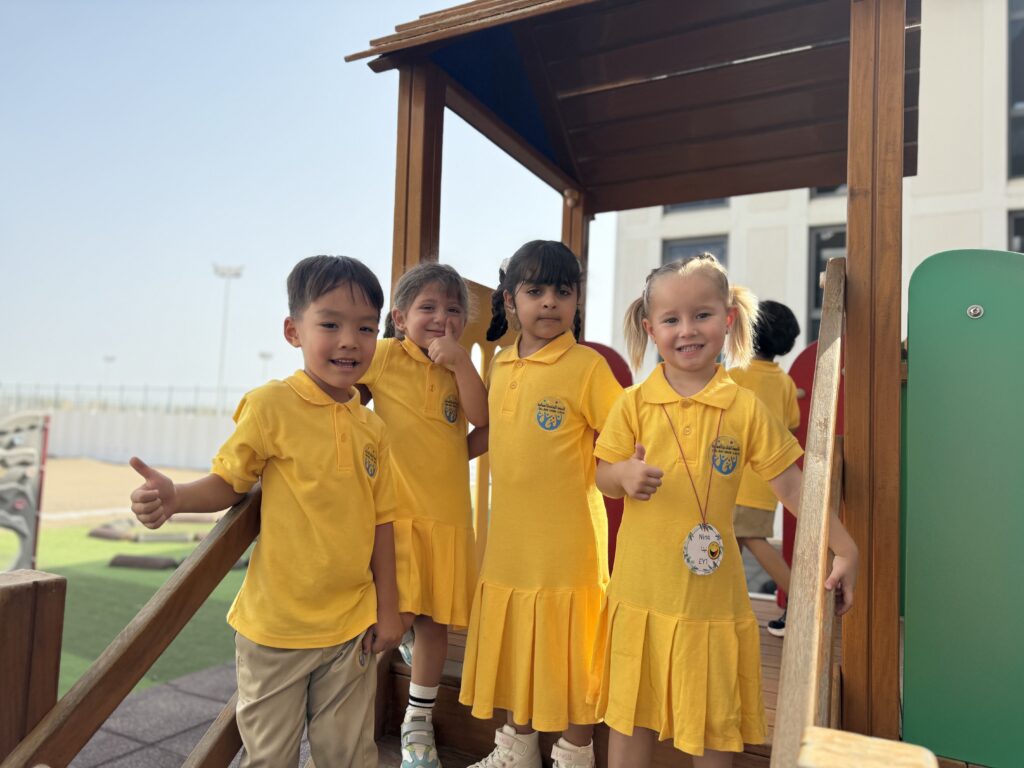 Students smiling at camera in a playground